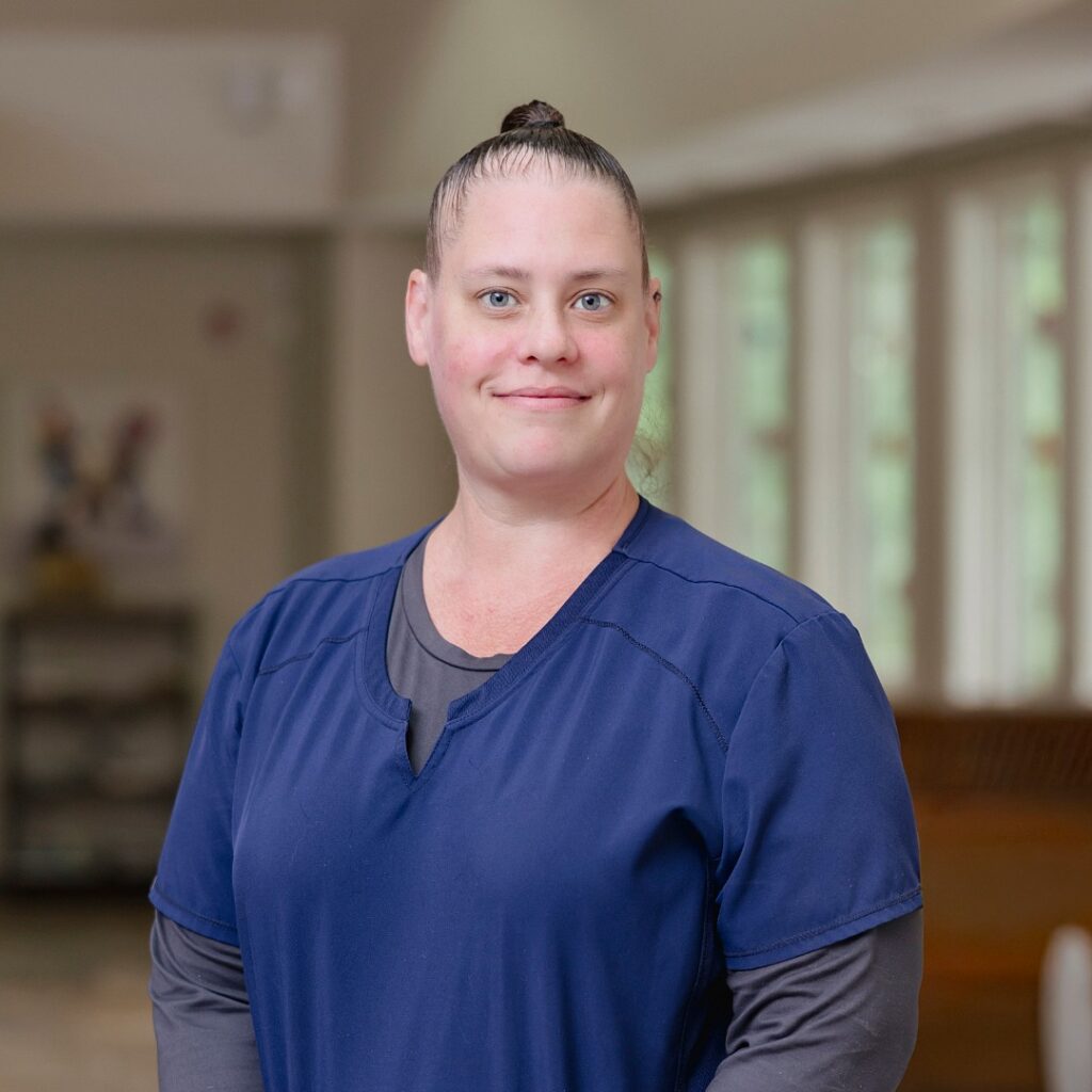 Kelly B - female with hair pulled back wearing blue scrubs